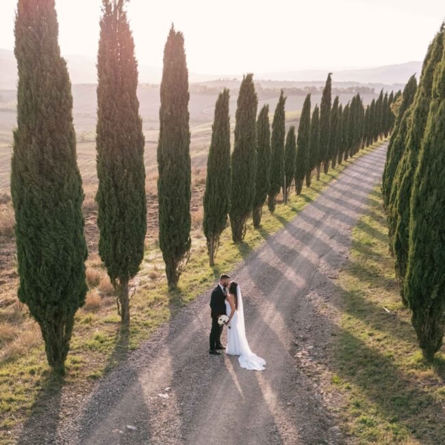 Bride and groom walking through Val d’Orcia hills during a romantic Tuscany wedding